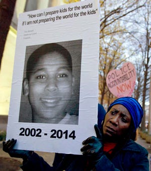 FILE - In this Dec. 1, 2014 file photo, Tomiko Shine holds up a picture of Tamir Rice, the 12 year old boy fatally shot by a rookie police officer in Cleveland, Ohio, on Nov. 22, during a protest in Washington, D.C. Twelve-year-old Tamir Rice was fatally shot by a Cleveland police officer near a gazebo in a recreational area in November 2014. Officers were responding to a report of a man waving a gun. The boy, who had a pellet gun tucked in his waistband, was shot right after their cruiser skidded to a stop a few feet away. A grand jury in December 2015 declined to indict patrolman Timothy Loehmann, who fired the fatal shot, and training officer Frank Garmback. The city in 2016 agreed to settle a federal lawsuit filed by Tamir Rice’s family for $6 million. (AP Photo/Jose Luis Magana, File)