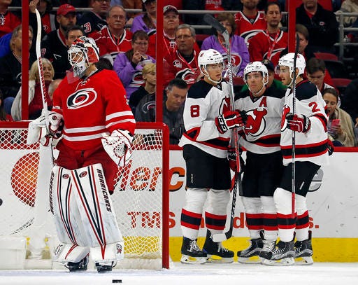 New Jersey Devils' Michael Cammalleri, center, celebrates his goal with teammates Beau Bennett (8) and John Moore (2) with Carolina Hurricanes goalie Eddie Lack (31) nearby during the second period of an NHL hockey game, Sunday, Nov. 6, 2016, in Raleigh, N.C. The Devils won 4-1. (AP Photo/Karl B DeBlaker)
