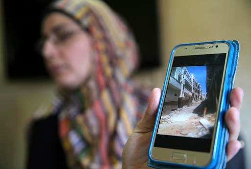 In this picture taken on Friday, Oct. 3, 2016, Hoda a Syrian displaced woman shows through her mobile phone the empty street of her house at Baba Tadmor neighborhood in Homs province, as she speaks during an interview with the Associated Press, in Tripoli, north Lebanon. Syrian opposition figures and refugees point to an array of obstacles facing the displaced who want to return home, saying that the government is machinating to discourage potentially restive populations from returning to areas they fled during the war. (AP Photo/Hussein Malla)