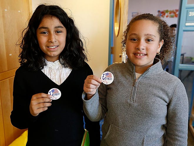 Isabella Renaud and Marialba Peguero, both fifth graders, show off their I voted stickers in a mock presidential election at the George Elementary School in Brockton on Monday, Nov.7, 2016.
