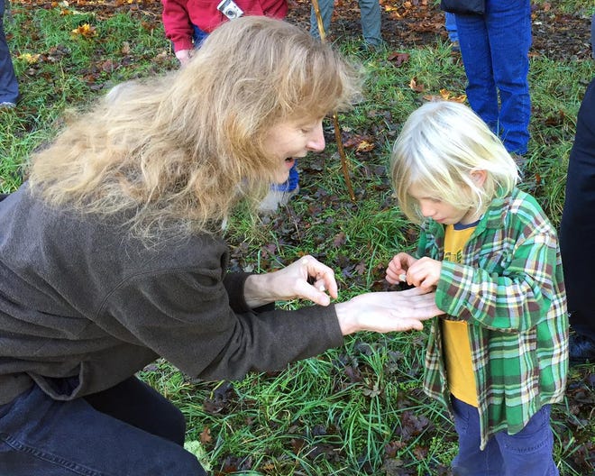 Molly Widmer of the Cascade Mycological Society examines a mushroom with a child during a nature walk Sunday at the Mount Pisgah Arboretum. (Christian Hill/The Register-Guard)