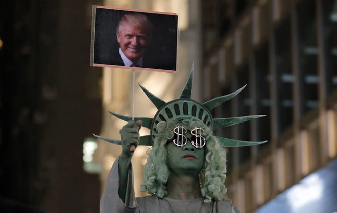 A street performer dressed as the Statue of Liberty holds up a picture of U.S. President-elect Donald Trump in Hong Kong's downtown on Wednesday, Nov. 9, 2016.