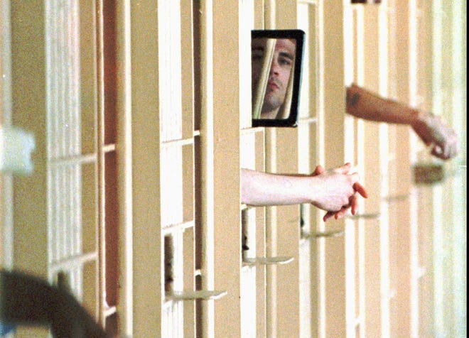 A death row inmate in the Florida State Prison views a photographer using a hand mirror. Despite many death sentences, only 92 people have been executed by the state of Florida since 1972. AP FILE PHOTO
