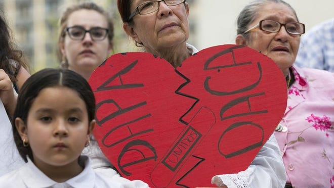 Angela Reyes holds a sign while participating in a vigil at the Governor’s Mansion on June 23 in response to a Supreme Court decision that put on hold an executive action by President Barack Obama that would have shielded an estimated 5 million immigrants from deportation, including those who came to the country as children.