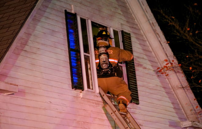 A Rochester firefighter enters a home through a window Thursday night in Lebanon, Maine. Shawn St. Hilaire/Fosters.com