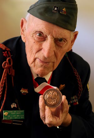 Ninety-three-year-old World War II veteran Ray Stewart, a tank driver/gunner in the Battle of the Bulge, shows off his Order of St. George medallion from the U.S. Cavalry and Armor Association on Thursday afternoon at his home on Ann Street in Gastonia. PHOTO MIKE HENSDILL/THE GAZETTE