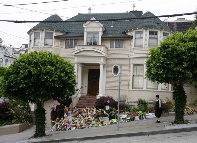 FILE - In this Aug. 15, 2014 file photo, a woman stops to look at a makeshift memorial for actor Robin Williams outside a home which was used in the filming of the movie “Mrs. Doubtfire” in San Francisco. The iconic “Mrs. Doubtfire” house, which served as a temporary shrine to Williams after his suicide in 2014, has sold for $4.15 million. (AP Photo/Eric Risberg, file)