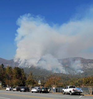 People take photos of a wildfire burning near Lake Lure, N.C., Thursday, Nov. 10, 2016. A state of emergency is in effect for 25 western North Carolina counties where active wildfires are burning, caused by the drought that began last spring. Gov. Pat McCrory said in a news release Thursday that he was declaring the state of emergency for one-quarter of North Carolina’s 100 counties. (Patrick Sullivan/The Times-News via AP)