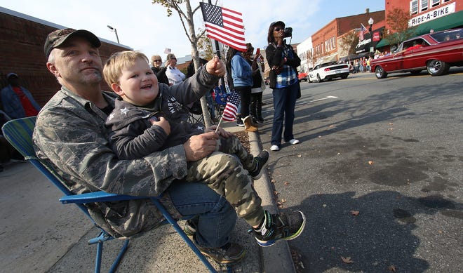 The annual Veterans Day Parade mades its way along Main Avenue in downtown Gastonia Friday morning much to the delight of hundreds of parade goers. Here, veteran Steve Will and his son Raylan Will (4) watch the parade together. PHOTO MIKE HENSDILL/THE GAZETTE