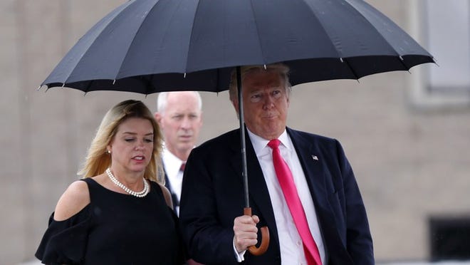 FILE - In this Aug. 24, 2016 file photo, Republican presidential candidate Donald Trump walks in the rain with Florida Attorney General Pam Bondi as they arrive at a campaign rally in Tampa, Fla. House Democrats are calling for a federal criminal investigation into an improper $25,000 donation Trump's charity made to a political group supporting Florida's attorney general after her office said it was weighing legal action against Trump University. In a letter that all 16 Democrats on the House Judiciary Committee sent Sept. 13 to U.S. Attorney General Loretta Lynch, ranking member John Conyers of Michigan said federal investigators should determine whether the 2013 donation and Bondi's decision not to join the New York lawsuit violated federal bribery or tax laws.(AP Photo/Gerald Herbert, File)