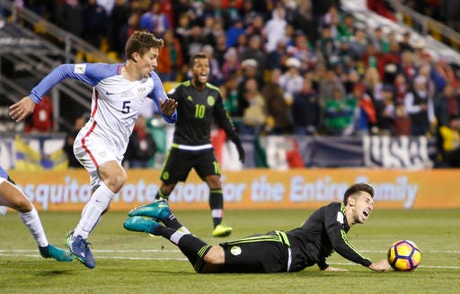 Mexico's Hector Herrera, right, falls to the ground as United States' Matt Besler looks for the ball during the second half of a World Cup qualifying soccer match Friday, Nov. 11, 2016, in Columbus, Ohio. (AP Photo/Jay LaPrete)