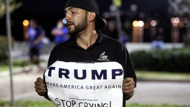 Donald Trump supporter Sergio Fraguela of West Palm Beach was one of the few Donald Trump supporters to attend an anti-Trump rally Friday, Nov. 11, 2016 in front of the luxury condominium towers that bear his name along the waterfront in West Palm Beach. (Damon Higgins / The Palm Beach Post)