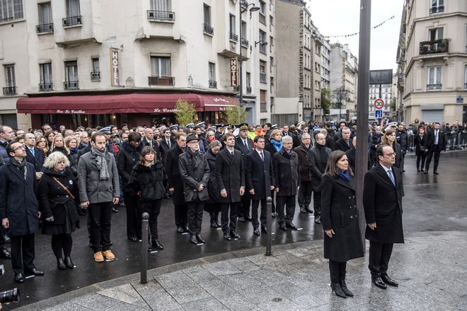 French President Francois Hollande and Paris Mayor Anne Hidalgo stand at attention after unveiling a commemorative plaque near the Petit Cambodge and Carillon cafes in Paris, France, during a ceremony held for the victims of last year’s Paris attacks which targeted the Bataclan concert hall as well as a series of bars and killed 130 people. (Christophe Petit Tesson/Pool Photo via AP)