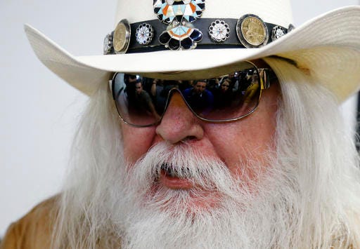 In this Jan. 29, 2013, file photo, reporters are reflected in the sunglasses of Leon Russell as he answers a question at a news conference in Tulsa, Okla. Russell, who sang, wrote and produced some of rock ‘n’ roll’s top records, has died. (AP Photo/Sue Ogrocki, File)