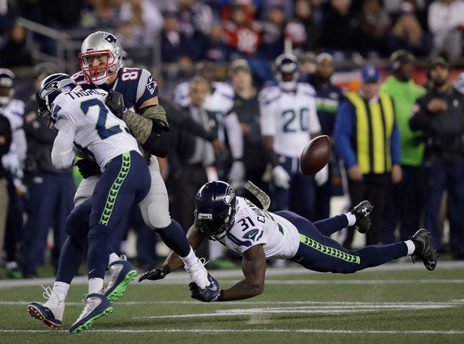 Seattle Seahawks safety Earl Thomas, left, slams New England Patriots tight end Rob Gronkowski on a pass play as Seahawks safety Kam Chancellor pursues during the first half of an NFL football game, Sunday, Nov. 13, 2016, in Foxboro.