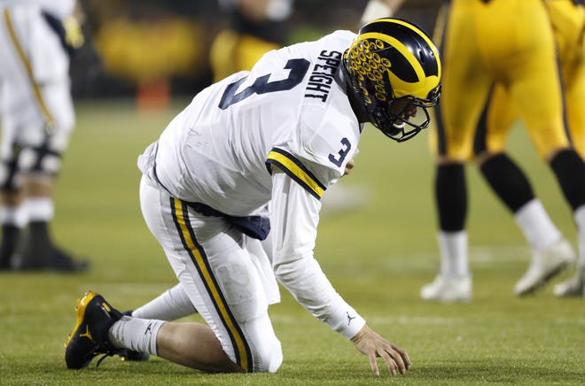 Michigan quarterback Wilton Speight kneels on the turf after getting hit during the second half of the team's NCAA college football game against Iowa, Saturday, Nov. 12, 2016, in Iowa City, Iowa. Iowa won 14-13. (AP Photo/Charlie Neibergall)
