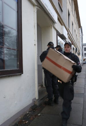 Police officers carry cardboard boxes out of a mosque in Hamburg, northern Germany, Tuesday, Nov. 15, 2016 when hundreds of police officers search about 190 offices, mosques and apartments of members and supporters of the Islamic group The true religion in Germany after the German government announced a ban of the organization early Tuesday. (Christian Charisius/dpa via AP)