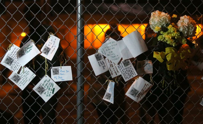 Notes remembering Matthew Gardner are on display as students speak behind a fence Monday at Rutherford High School. Gardner, a senior, died Monday of brain cancer. PATTI BLAKE/THE NEWS HERALD