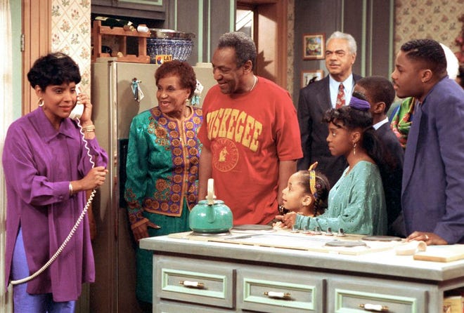 In this March 6, 1992, file photo, Phylicia Rashad, as Clair Huxtable, talks on the telephone while Bill Cosby, as Dr. Cliff Huxtable, center, and other cast members of the family sitcom "The Cosby Show," gather around during taping of the final episode in New York. Bounce TV announced Nov. 11, 2016, that it would resume airing reruns of "The Cosby Show" on Dec. 19.