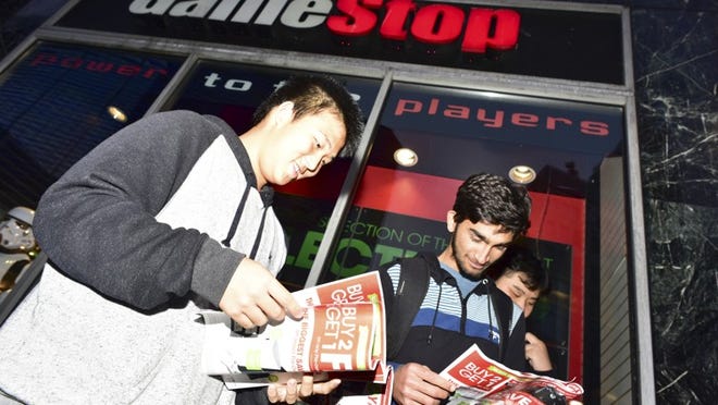 Swen-Chi Chu and Usama Youseaf at a Gamestop on Black Friday in New York, Nov. 27, 2015. Recent market research shows that physical game sales declined in November, and GameStop, a leading retailer, reported disappointing earnings that made its stock tumble. (Dolly Faibyshev/The New York Times)