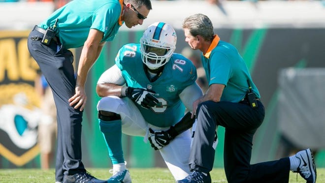 Miami Dolphins offensive tackle Branden Albert (76) is checked by trainers on the field at EverBank Field in Jacksonville, Florida on September 20, 2015. (Allen Eyestone / The Palm Beach Post)