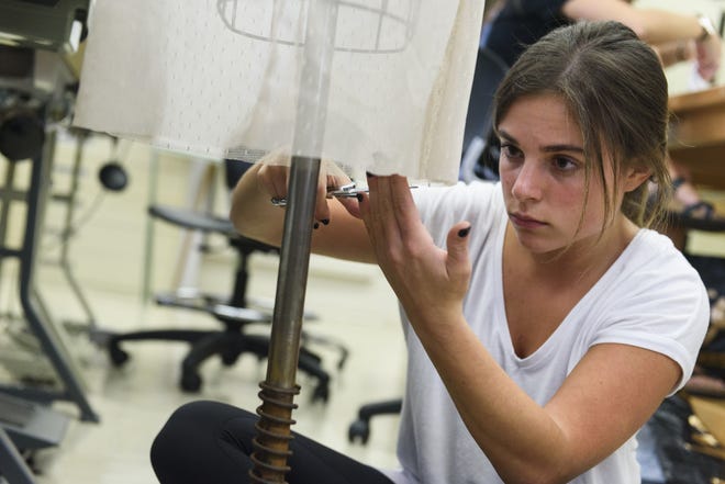 Student designer Katherine Lowenthal does some hem work on one of the pieces in her senior collection. Photo provided by the University of Alabama