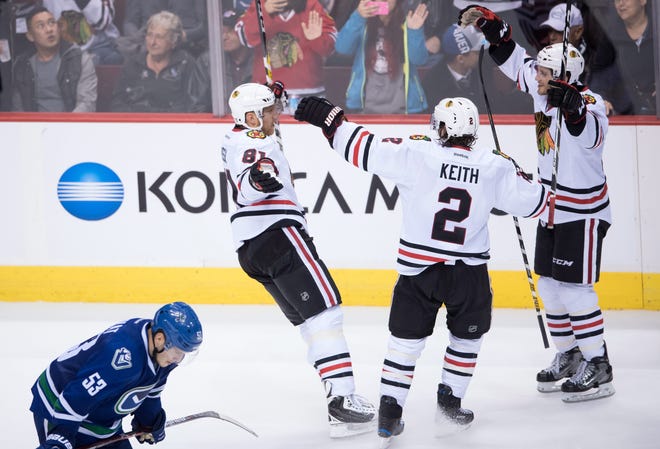 Chicago Blackhawks' Marian Hossa, of Slovakia, top from left to right, Duncan Keith and Ryan Hartman celebrate Hossa's winning goal in front of Vancouver Canucks' Bo Horvat, bottom left, during the overtime period of an NHL hockey game in Vancouver, British Columbia, on Saturday Nov. 19, 2016. (Darryl Dyck/The Canadian Press via AP)