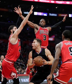 Los Angeles Clippers' Blake Griffin, center, is defended by Chicago Bulls' Dwyane Wade, top, and Nikola Mirotic, left, during the first half of an NBA basketball game Saturday, Nov. 19, 2016, in Los Angeles. (AP Photo/Jae C. Hong)
