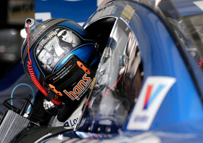 Jimmie Johnson gets in his car as he prepares for the NASCAR Sprint Cup Series auto practice Saturday, Nov. 19, 2016, in Homestead, Fla. On the back of Johnson's helmet, Dale Earnhardt, left, and Richard Petty, right are pictured, both have seven series championships, as Johnson with six championships is chasing his seventh. (AP Photo/Terry Renna)