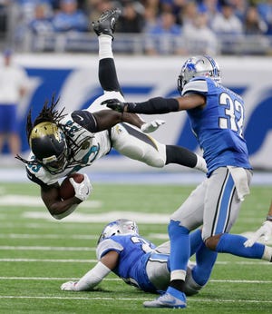 Jacksonville running back Chris Ivory (left) leaps over a Detroit defender during the second half. Ivory had 39 yards rushing and a fumble in Sunday’s loss. (Duane Burleson/AP Photo)