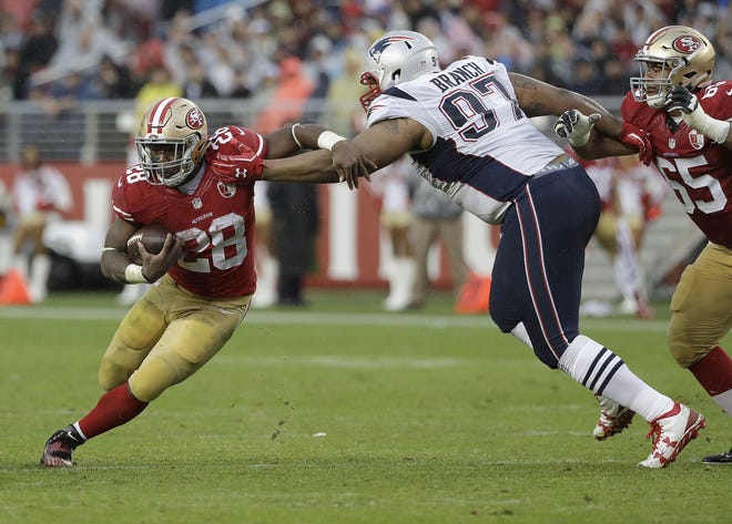 San Francisco 49ers running back Carlos Hyde (28) is grabbed by New England Patriots defensive tackle Alan Branch (97) during the first half of their game in Santa Clara, Calif., Sunday. Photo by AP