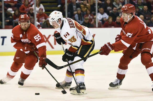 Calgary Flames center Sam Bennett (93) has the puck knocked away by Detroit Red Wings defenseman Niklas Kronwall (55) of Sweden and center Dylan Larkin (71) during the first period of an NHL hockey game in Detroit, Sunday, Nov. 20, 2016. (AP Photo/Jose Juarez)