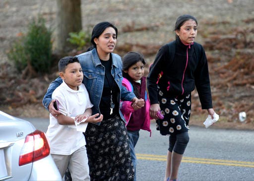 A woman escorts three children away from the scene of a fatal school bus wreck in Chattanooga, Tenn., Monday, Nov. 21, 2016. In a news conference Monday, Assistant Chief Tracy Arnold said there were multiple fatalities. (Angela Lewis Foster/Chattanooga Times Free Press via AP)
