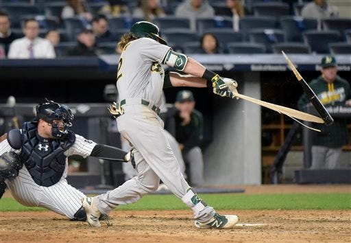 In this April 19, 2016 file photo, the Oakland Athletics’ Josh Reddick breaks his bat while flying out as New York Yankees catcher Brian McCann watches during the fifth inning of a game at Yankee Stadium in New York. (Bill Kostroun/AP Photo)