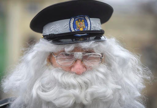 A Romanian policeman wears a false beard and glasses covered in tape to suggest old age and blurred vision during a protest demanding the lowering of the retirement age for police officers in Bucharest, Romania, Wednesday, Nov. 22, 2016. The protest was joined by more than one thousand officers asking the government to lower retirement age which is currently 65 years-old. (AP Photo/Andreea Alexandru)