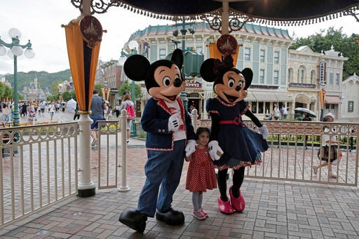FILE - In this June 10, 2016, file photo, a girl poses with Mickey and Minnie Mouse at the Hong Kong Disneyland in Hong Kong. Hong Kong officials said Tuesday, Nov. 22, 2016 they signed an agreement for a $1.4 billion expansion of the southern Chinese city’s Disneyland theme park. The government said the plan calls for adding two new themed areas, based on the movie “Frozen” and characters from “Marvel Super Heroes,” to Hong Kong Disneyland. (AP Photo/Kin Cheung, File)