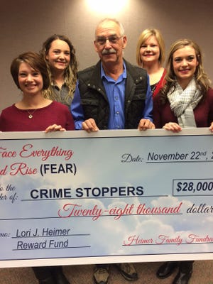 The four daughters and husband of rural Assaria murder victim Lori Heimer present a $28,000 check Tuesday to Salina/Saline County Crimestoppers at Salina Public Library. Pictured with the check are (from left) Genell Heimer, Lynnsey Heimer, Ronald Heimer, Katie Eberle and Joni Alexander.