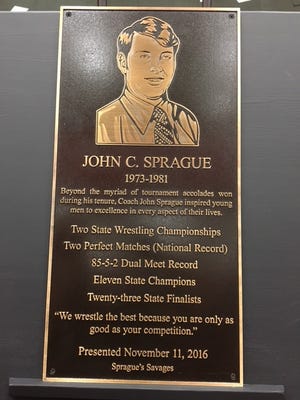 Rockdale High graduates who wrestled on John Sprague's team suprised their coach with a plaque and the naming of the wrestling portion of their new facility at the high school in Rockdale, Georgia. COURTESY PHOTO