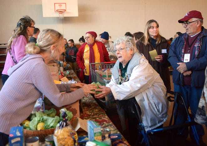 Edna Cusson, 88, of Danielson, receives pears from volunteer Donna Kharonian, of Danielson, for her Thanksgiving dinner, with volunteers Leeanne Lachapelle, of Woodstock, and Ed Godaire, of Moosup, right, Tuesday during the 26th annual Friends of Assisi Thanksgiving Distribution at St. James School in Danielson. See videos and more photos at NorwichBulletin.com John Shishmanian/ NorwichBulletin.com