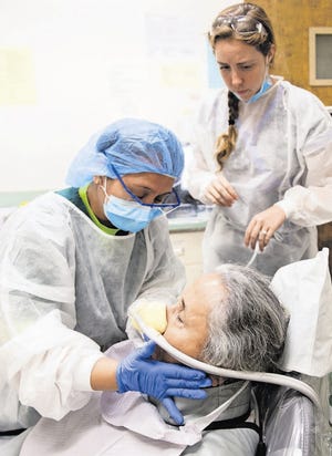 Student dentists at the Herman Ostrow School of Dentistry of USC in Los Angeles work on patient Violeta Anderson while she is sedated. HEIDI DE MARCO/KHN PHOTOS