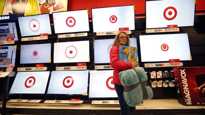 FILE - In this Nov. 28, 2014 file photo, a customer walks past a bank of flat screen televisions at a Target store in South Portland, Maine. Target Corp. reports quarterly financial results on Wednesday, Feb. 25, 2015. (AP Photo/Robert F. Bukaty, File)