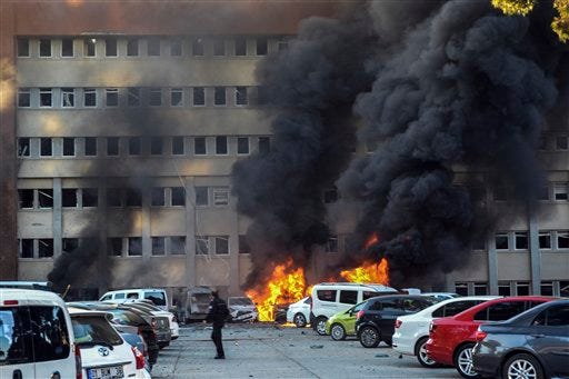 A police officer walks past by a fire after an explosion that killed people and wounded several others in southern city of Adana, Turkey, Thursday, Nov. 24, 2016. The explosion occurred early Thursday in the car park of a government building, officials said. Turkish authorities have banned distribution of images relating to the Adana explosion within Turkey. (AP Photo)