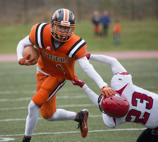 Newton North's Noah Neville breaks a tackle during the Tigers' 21-0 victory against Brookline. Cheryl Clegg Photo