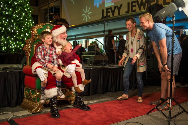Sam Brown has his pictures taken with Santa Claus as parents Julie and Zach attempt to comfort their their daughter Isla during the Christmas Tree lighting ceremony on Brought Street Friday night. (Josh Galemore/Savannah Morning News)