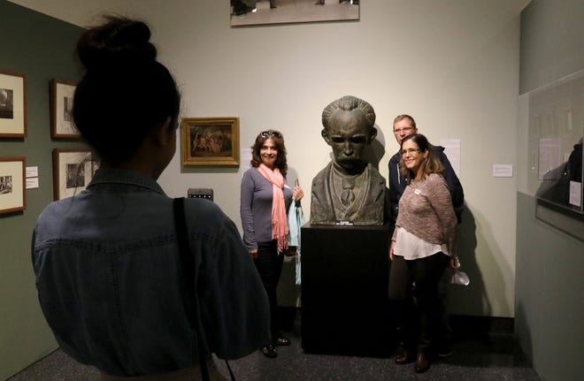 The Abela and Carballo families pose Saturday for a photo next to the bust of Juan Jose Sicre, who was known as the "George Washington of Cuba," which is on display at the Museum of Arts and Sciences in Daytona Beach. News-Journal/JIM TILLER