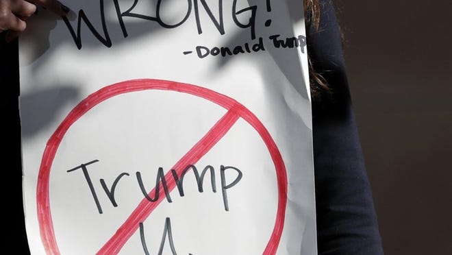 Senya Merchant holds a sign against President-elect Donald Trump’s now-defunct Trump University Friday, Nov. 18, 2016, in San Diego. Trump agreed Friday to pay $25 million to settle several lawsuits alleging that his former school for real estate investors defrauded students who paid up to $35,000 to enroll in Trump University programs.(AP Photo/Gregory Bull)