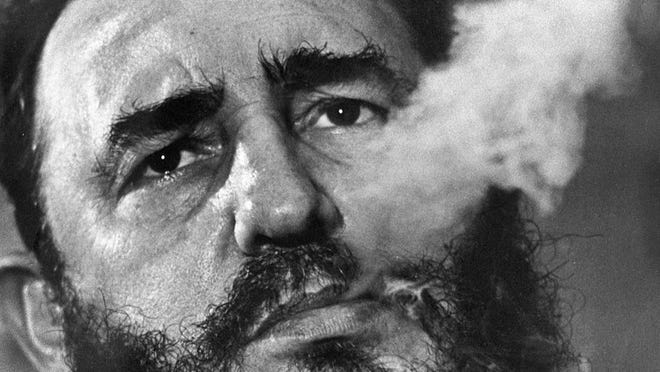 Fidel Castro exhales cigar smoke in this March 1985 file photo during an interview in Havana. He died late Friday at age 90, 57 years after leading a revolution and taking control of Cuba. (AP Photo/ Charles Tasnadi)