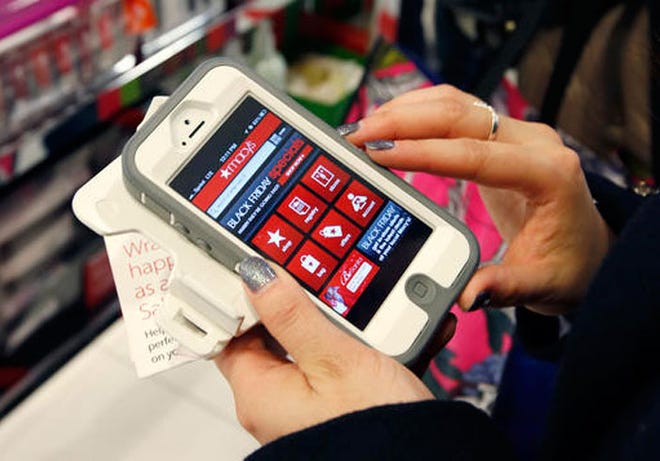 In this Friday, Nov. 23, 2012, file photo, Tashalee Rodriguez, of Boston, uses a smartphone app while shopping at Macy's in downtown Boston. Shoppers are flocking online Monday, Nov. 28, 2016, as "Cyber Monday" sales hit their peak. Each year, during the busy holiday shopping weekend that kicks off on Thanksgiving and the Friday after, known as Black Friday, more and more shoppers decide to skip the mayhem in stores and shop online.