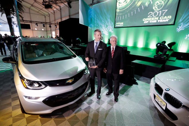 Ron Cogan (right), editor and publisher of the Green Car Journal, and Steve Majoros, director of Chevrolet Marketing, pose together after the 2017 Chevrolet Bolt EV was announced the winner of the Green Car of the Year Award during the Los Angeles Auto Show on Nov. 17. (Chris Carlson/Associated Press)