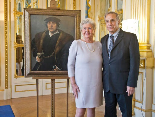Henrietta Schubert, left, and her cousin Christopher Bromberg pose next to a 16th century painting attributed to the school of Joos van Cleve, "Portrait of a Man," during a ceremony at the Culture Ministry in Paris, Monday, Nov. 28, 2016. The French government hands over an oil painting to the grandchildren of Henry and Hertha Bromberg acquired by the Nazis during World War II. (AP Photo/Michel Euler)